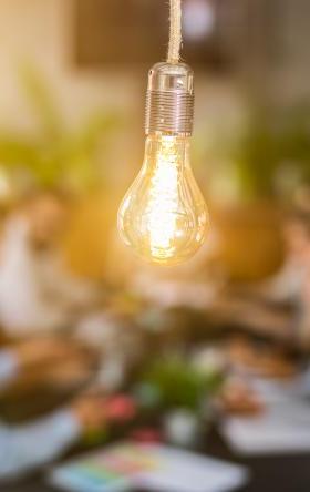 lightbulb in front of out of focus group of people at table